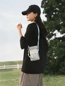 Detailed outdoor shot of the stylish plaid crossbody phone bag with blue straps on a model.