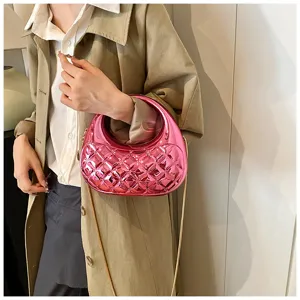 Detail shot of a shiny pink quilted acrylic handbag with round handle and gold chain strap.