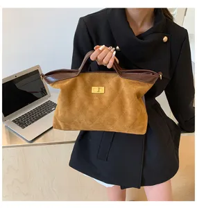 Detailed view of the vintage brown suede handbag with quilted pattern and gold turn-lock.