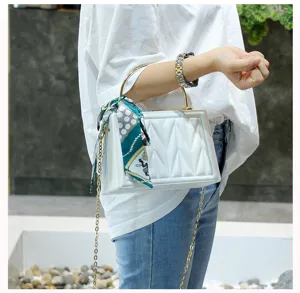 Stylish white quilted handbag with chain strap, metal handle and chic green silk scarf detail.