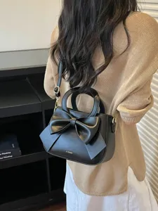 Stylish black leather shoulder handbag for women with elegant bow, versatile crossbody bag.