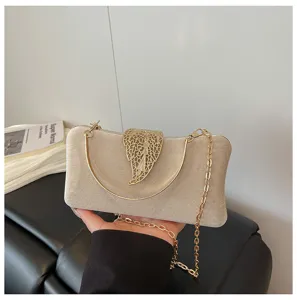 Detail view of champagne velvet evening clutch bag with gold leaf clasp and chain strap.