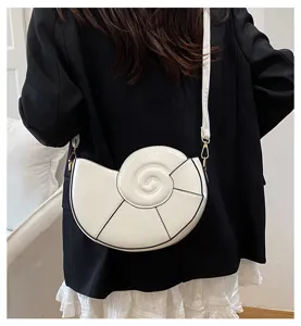 Vue détaillée du sac à bandoulière blanc élégant en forme de coquillage porté.