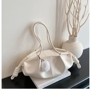 White leather shoulder bag with drawstring knot design and fluffy pom-pom charm detail.