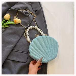 Exquisite pearl handle and sparkling shell clutch bag detail showing delicate gold chain strap.