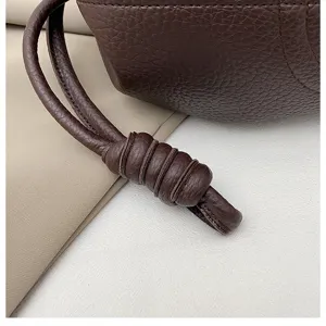 Detailed view of a stylish brown napa leather drawstring handbag with elegant knotted strap.