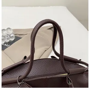 Dark brown leather handbag detail shot, premium Nappa texture, elegant top handle tote bag.