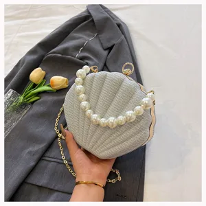 Detailed view of silver shell evening bag featuring elegant pearl handle and stylish gold chain.