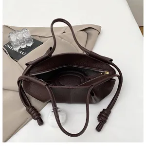 Dark brown napa leather dumpling bag with knotted handles and fluffy pom-pom detail.