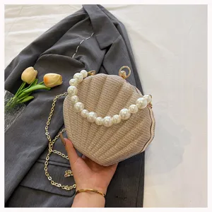 Detailed view of the sparkling shell evening bag with elegant pearl handle and gold chain strap.