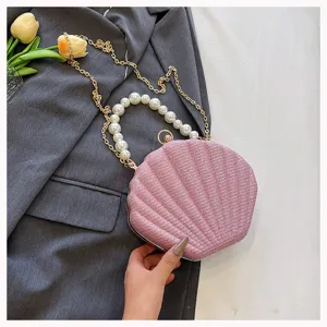 Pink sparkly shell evening bag detail featuring elegant pearl handle and gold chain strap.