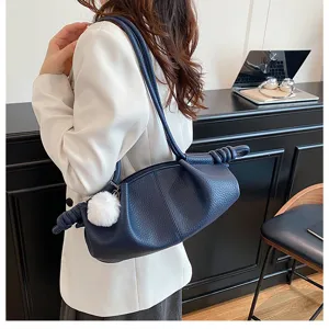 Detailed view of the dark blue leather shoulder bag with stylish knotted handles.