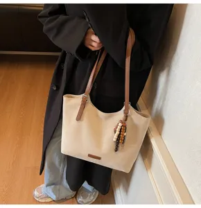 Detailansicht der Wildleder-Tasche mit braunen Riemen und Holzperlen-Anhänger-Dekor.