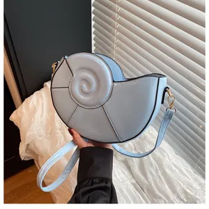 Gros plan détaillé du sac bandoulière coquillage bleu clair montrant la texture.