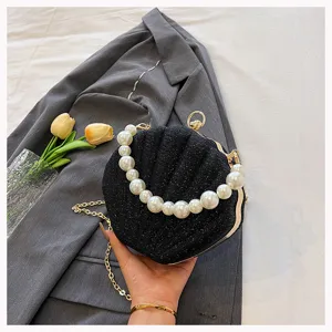 Detailed close-up view of the black shell evening bag highlighting the elegant pearl handle.