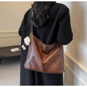 Stylish brown PU leather shoulder bag with chain strap and cute plush pendant for women.