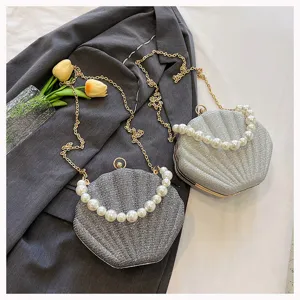 Fashionable glitter shell crossbody bag with pearl handle and metal chain for evening parties.