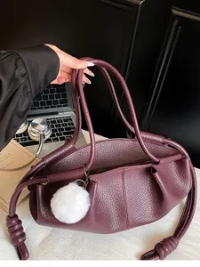 Stylish wine red Napa leather handbag featuring trendy knotted handles and fluffy charm.