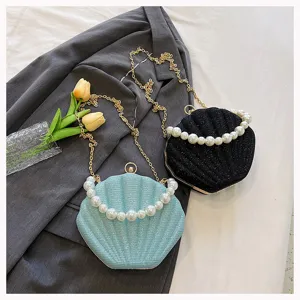 Close-up detail of stylish shell evening bag with pearl handle and gold chain strap.