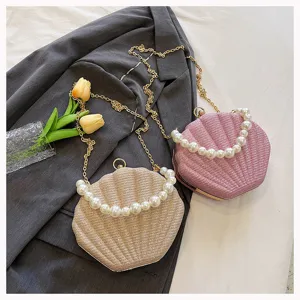 Detail view of shell evening bag with pearl handle and chain strap in champagne and pink colors.