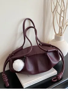 Chic burgundy leather dumpling shoulder bag with stylish knotted straps and pom-pom.