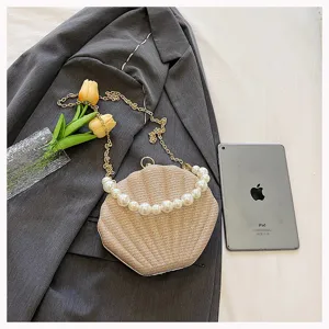Pearl shell crossbody evening bag with chic chain strap and elegant pearl handle design.