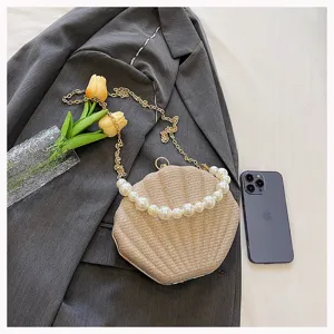 Detailed view of elegant shell evening clutch featuring pearl handle and metallic chain strap.