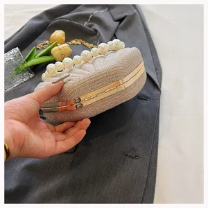 Elegant pearl handle shell clutch bag for women, sparkling evening handbag with metallic frame.