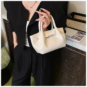 Close-up detail of white faux leather handbag with cute bow and twin top handles.