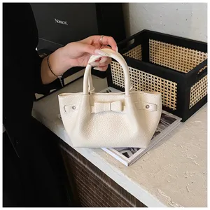 Chic white PU leather mini bucket bag featuring cute bow and stylish side belt design.
