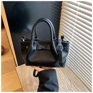 Detailed close-up of the black leather texture bucket bag featuring a cute bow and side strap.