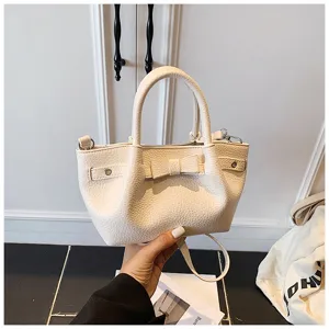 White leather bucket bag detail featuring a cute bow and side strap accents, chic design.