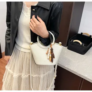 Trendy white bucket bag with wooden beads pendant, versatile crossbody shoulder handbag for women.