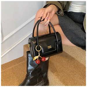 Sac à main carré vintage élégant avec pendentif cerise et finition noire brillante.