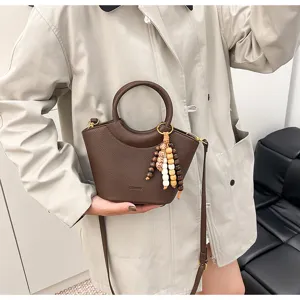 Trendy brown leather bucket bag for women, stylish shoulder and crossbody handbag.