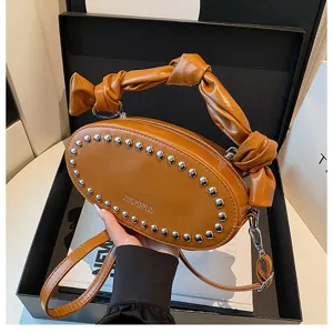 Stylish brown glossy leather crossbody bag with metal studs and a unique knotted handle design.