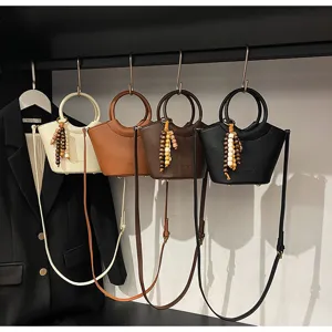 Trendy fashionable bucket bag with round handle and wooden bead tassel, versatile crossbody bag.