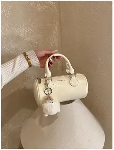 Detailed view of women fashion cylinder boston bag with cute plush charm and handle.