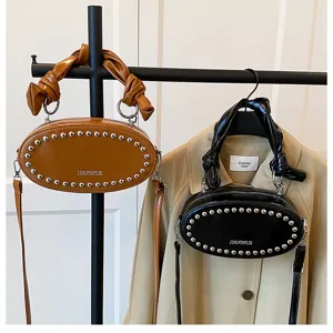 Trendy leather oval crossbody bag with metal rivets and stylish gathered cloud handle design