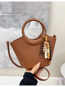 Trendy brown leather bucket handbag with wooden bead charms, stylish single shoulder crossbody bag.