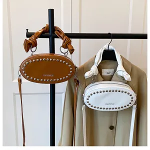 Detailed view of trendy PU leather oval crossbody bag with metal studs and gathered cloud handle.