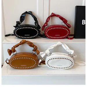 Stylish women's oval shoulder bag with metal studs and knotted handle in four classic colors.