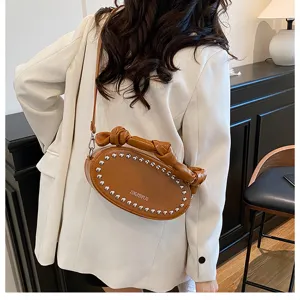 Stylish brown leather crossbody bag with chic rivets and knot strap detail, perfect detail view.