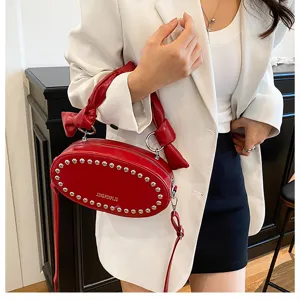 Red PU leather crossbody bag with metal rivets and unique knotted handle design for women
