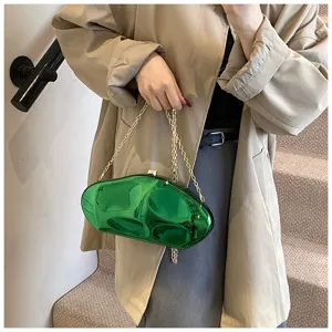 Green glossy acrylic clutch bag detail showing unique abstract shape and gold chain strap.