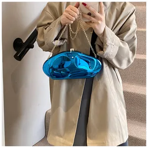 Detailed shot of unique blue acrylic abstract clutch bag with gold chain strap on model.