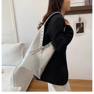 Detailed view of silver metallic shoulder tote bag with eyelets and side tie design.