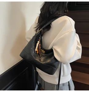 Borsa a tracolla hobo nera in pelle trapunta con catena e ciondolo con nappina di perline.