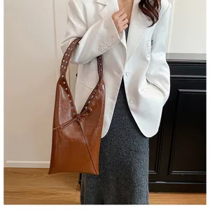 Detailed shot of a brown glossy hobo shoulder bag with metal eyelets and a knot accent.