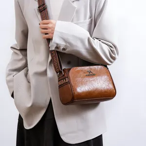 Detailed view of brown leather shoulder bag, textured fabric, adjustable wide strap.